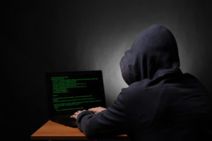 Hacker with laptop initiating cyber attack