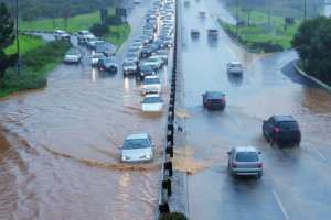 Traffic on a multi-lane road, with one side experiencing severe flooding showcasing the Essential Strategies to Navigating Rising Auto Insurance Costs.