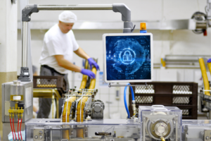 Food production facility with worker and cyber security screen, highlighting the importance of Cyber Liability Insurance for industrial cybersecurity