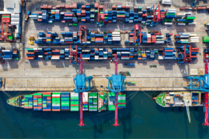 Aerial view of a busy shipping port with cargo containers and freight ships—highlighting the logistics and hidden cost of freight insurance.